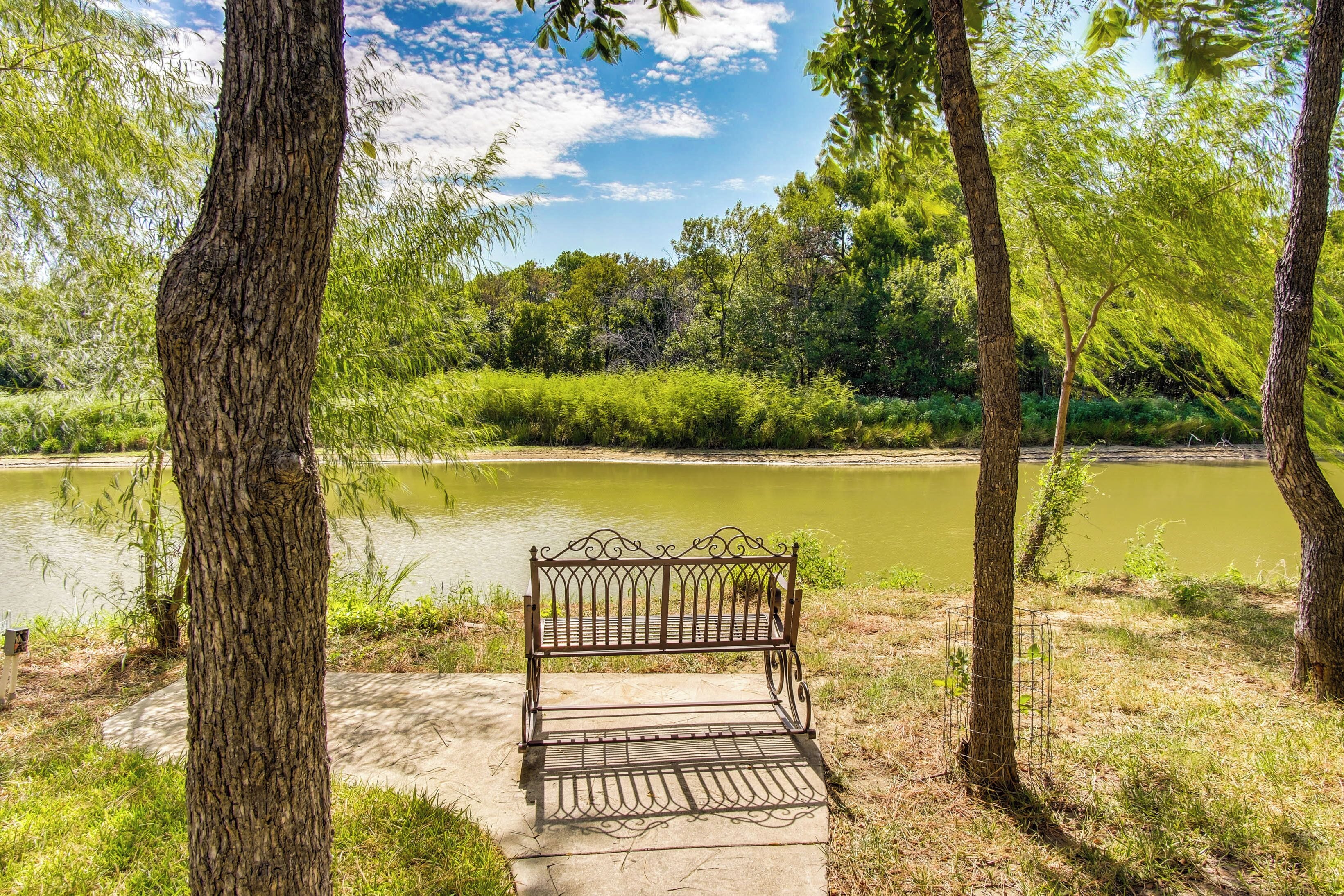 A bench in a park with a river in the background.