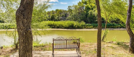 A bench in a park with a river in the background.