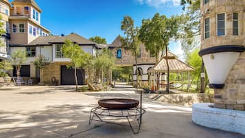 A courtyard with a fire pit, stone buildings, and a gazebo.