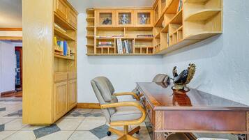 Une pièce comprenant un bureau en bois, une chaise, une bibliothèque et un objet décoratif posé sur le bureau.