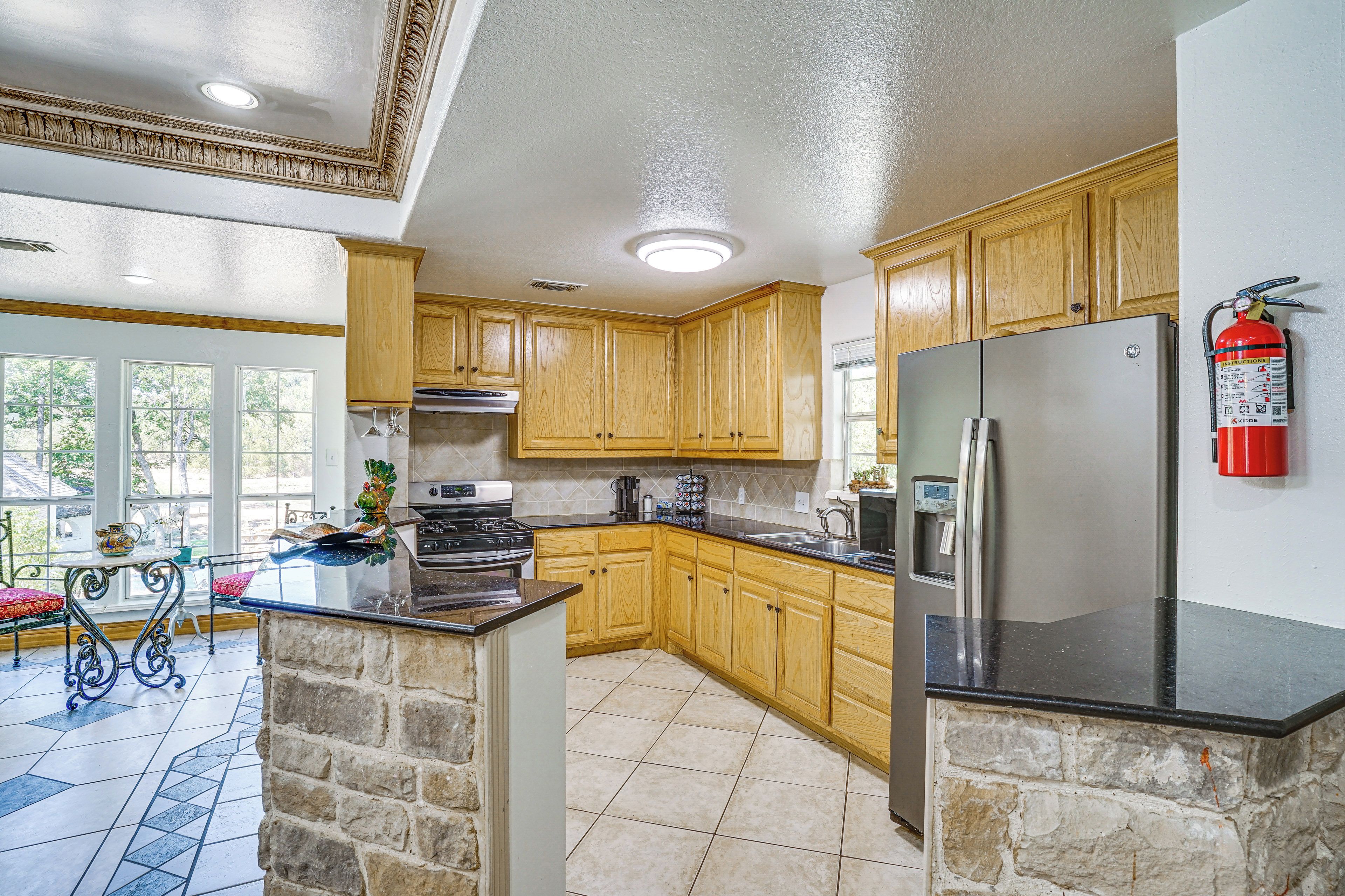 A kitchen with wooden cabinets, a stainless steel refrigerator, and a stone accent wall.