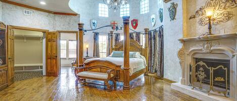 Um quarto espaçoso com cama de dossel, lareira e lustre.