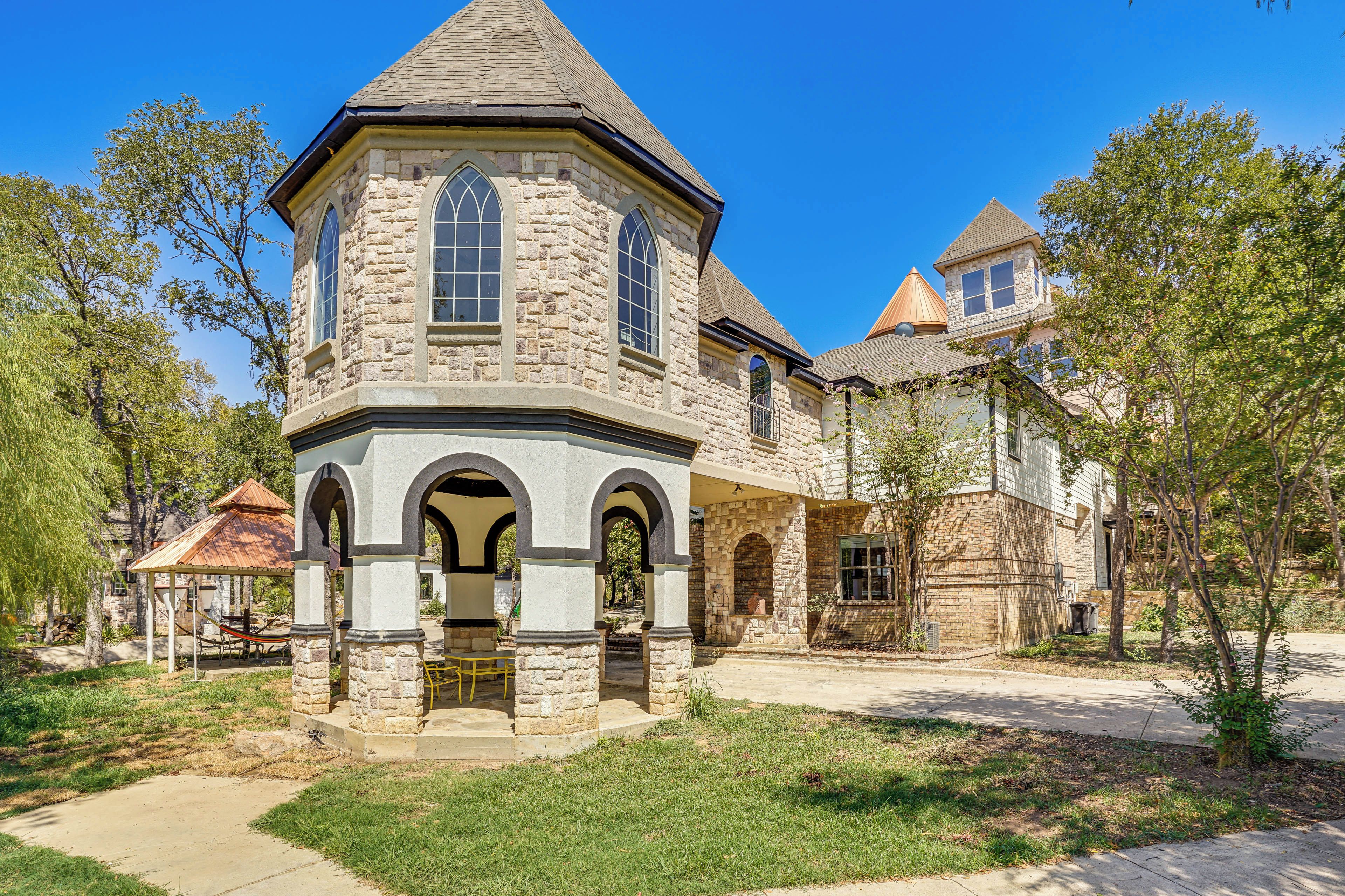 A stone building with a central tower, arched windows, and a covered patio area.