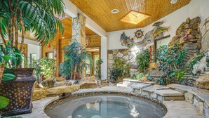 A spacious indoor area with a central hot tub, surrounded by stone walls and various plants. - Family Retreat Ready! 'castlewood Ranch' in Chico (Chico)