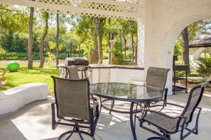 An outdoor patio with a glass table and four chairs, a grill, and a white brick wall. - Family Retreat Ready! 'castlewood Ranch' in Chico (Chico)