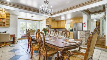 A dining area with a large wooden table, ornate chairs, and a chandelier.