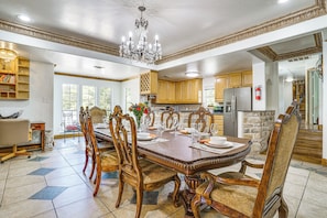 A dining area with a large wooden table, ornate chairs, and a chandelier.