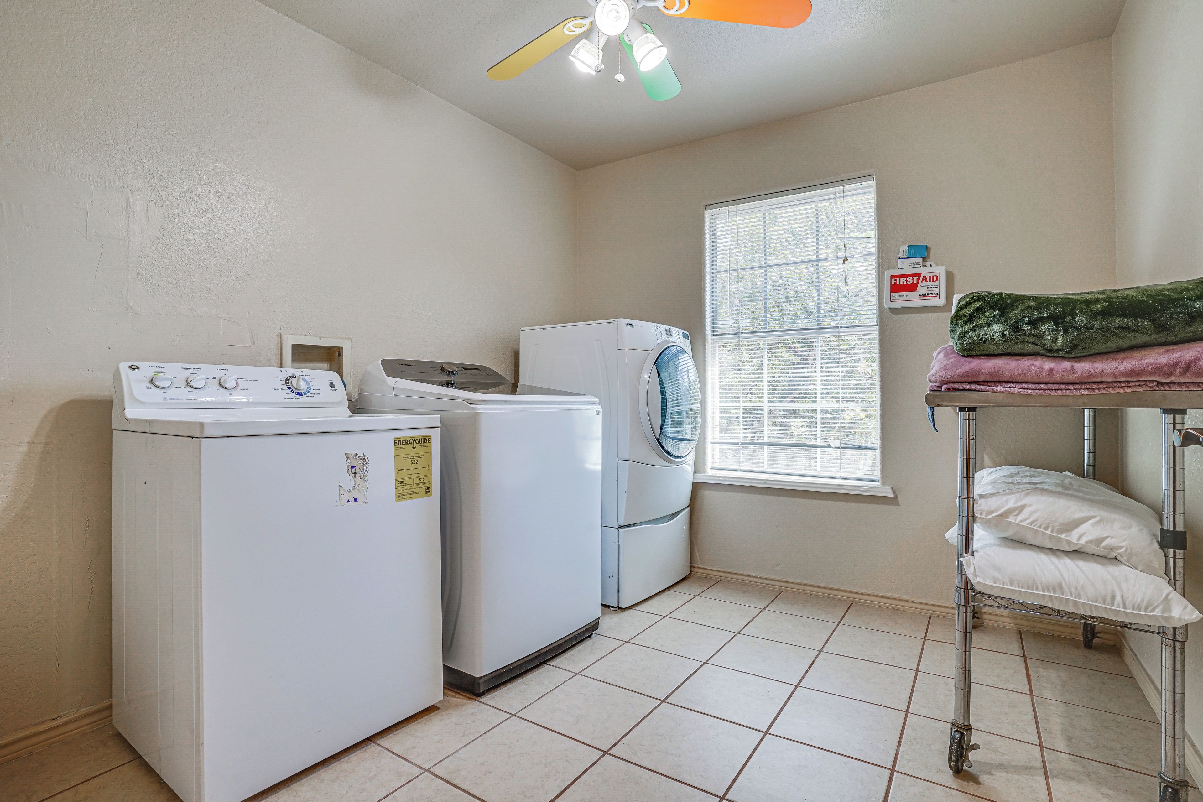 A laundry room with a washing machine, dryer, and a window with blinds.