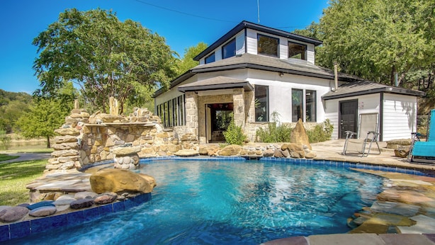 Una casa moderna con piscina, paisajismo de piedra y garaje.