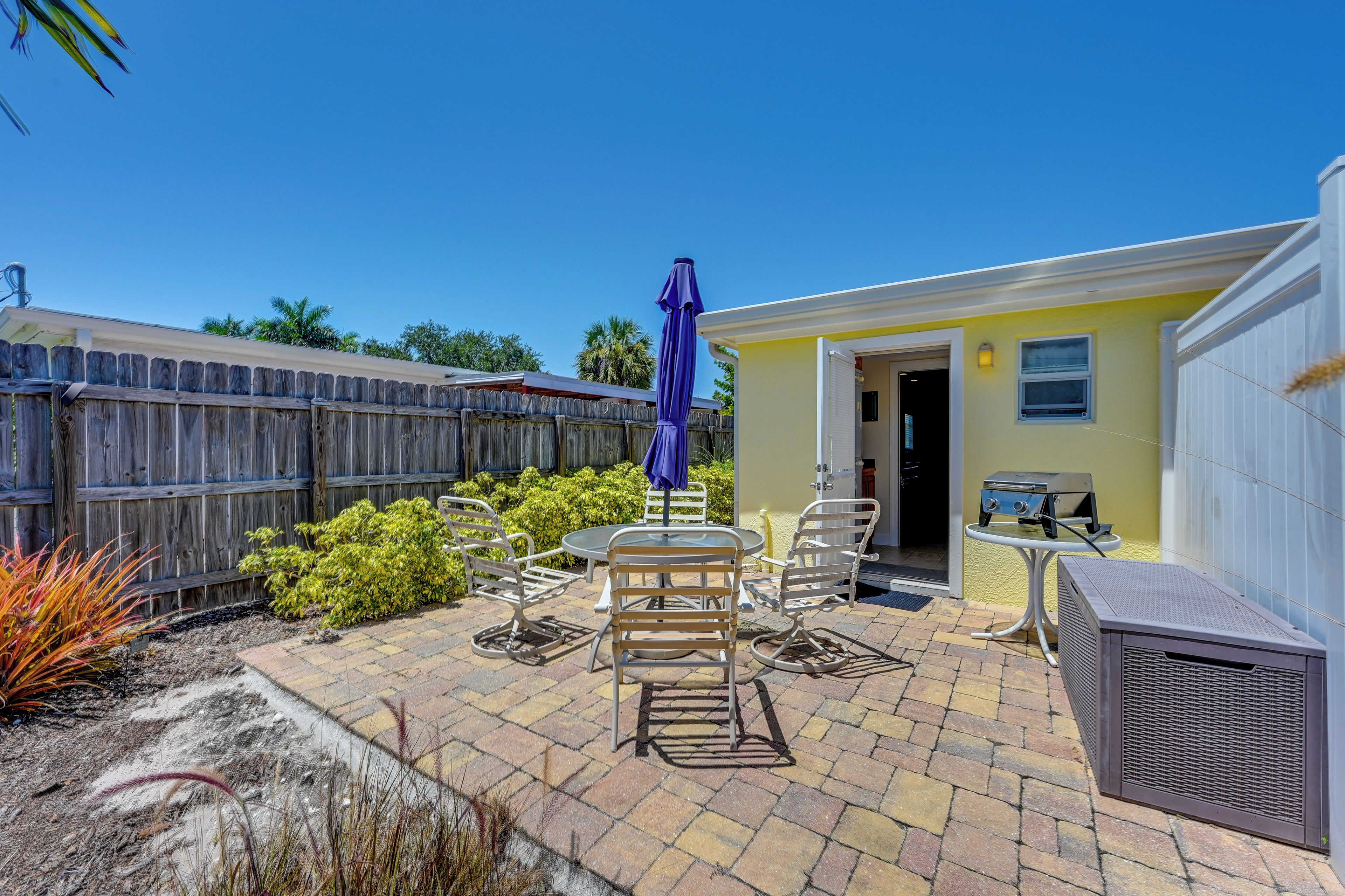 A patio area with outdoor furniture, a barbecue grill, and a yellow building.
