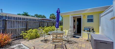 A patio area with outdoor furniture, a barbecue grill, and a yellow building.
