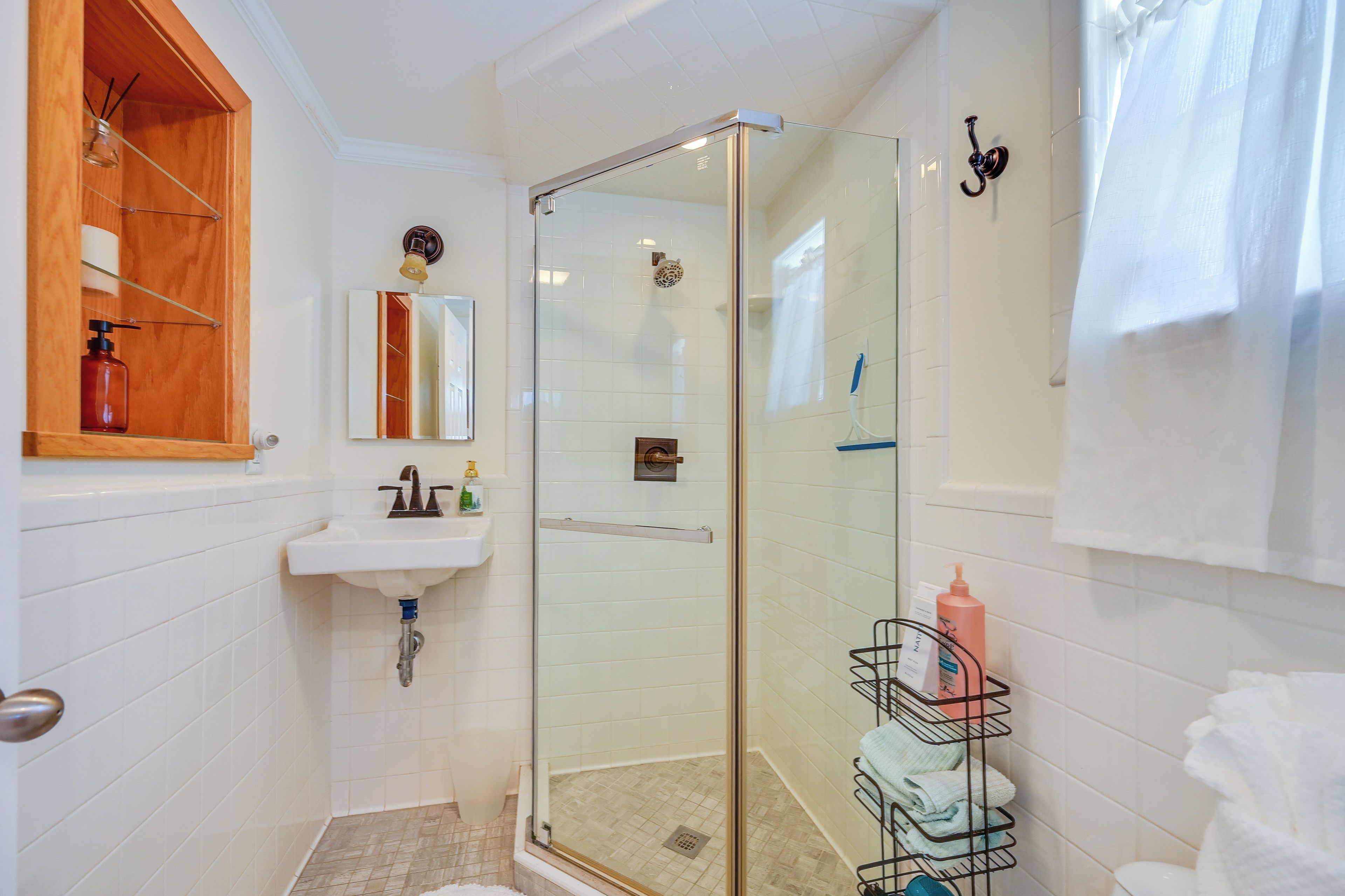 Un baño con cabina de ducha de vidrio, un lavabo con espejo y un perchero para toallas.