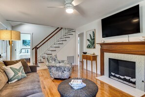 A living room with a sofa, armchair, coffee table, fireplace, and a television mounted on the wall.