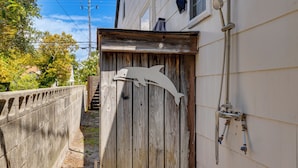 A wooden gate with a metal sculpture, a metal handrail, and a building with a window and a water spout.