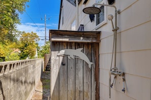 A wooden gate with a metal sculpture, a metal handrail, and a building with a window and a water spout.