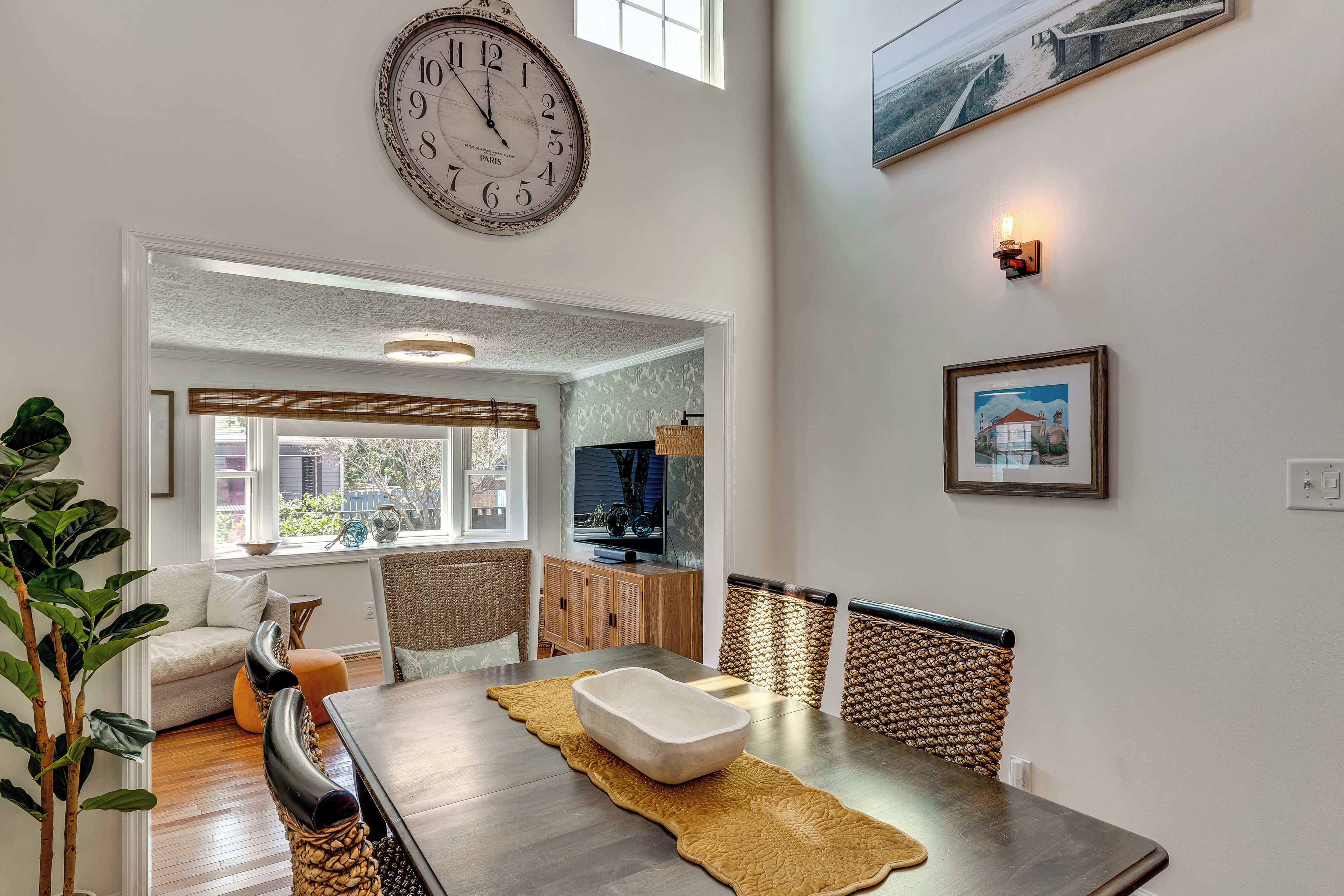 A dining area with a wooden table, chairs, and a large wall clock.