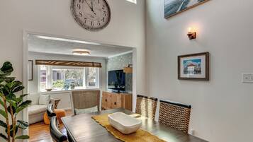 A dining area with a wooden table, chairs, and a large wall clock.
