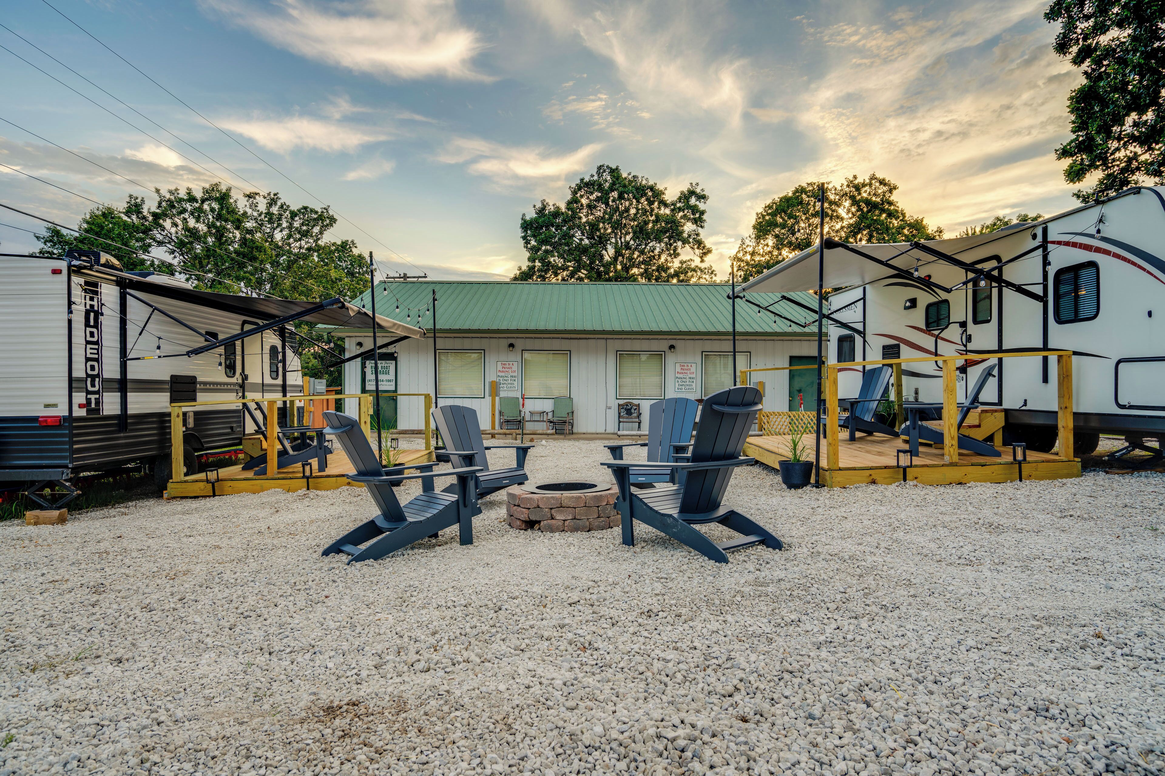 A gravel parking lot with RVs, a building with a green roof, and outdoor seating.