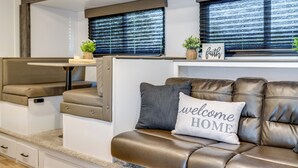Een modern interieur van een camper, met een bank, een tafeltje en een zitbank.