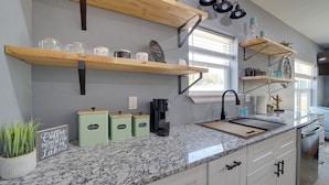 A kitchen with granite countertops, white cabinets, and wooden shelves. - Gateway to State Park & Lake! Inviting Vian Cabin (Gore)