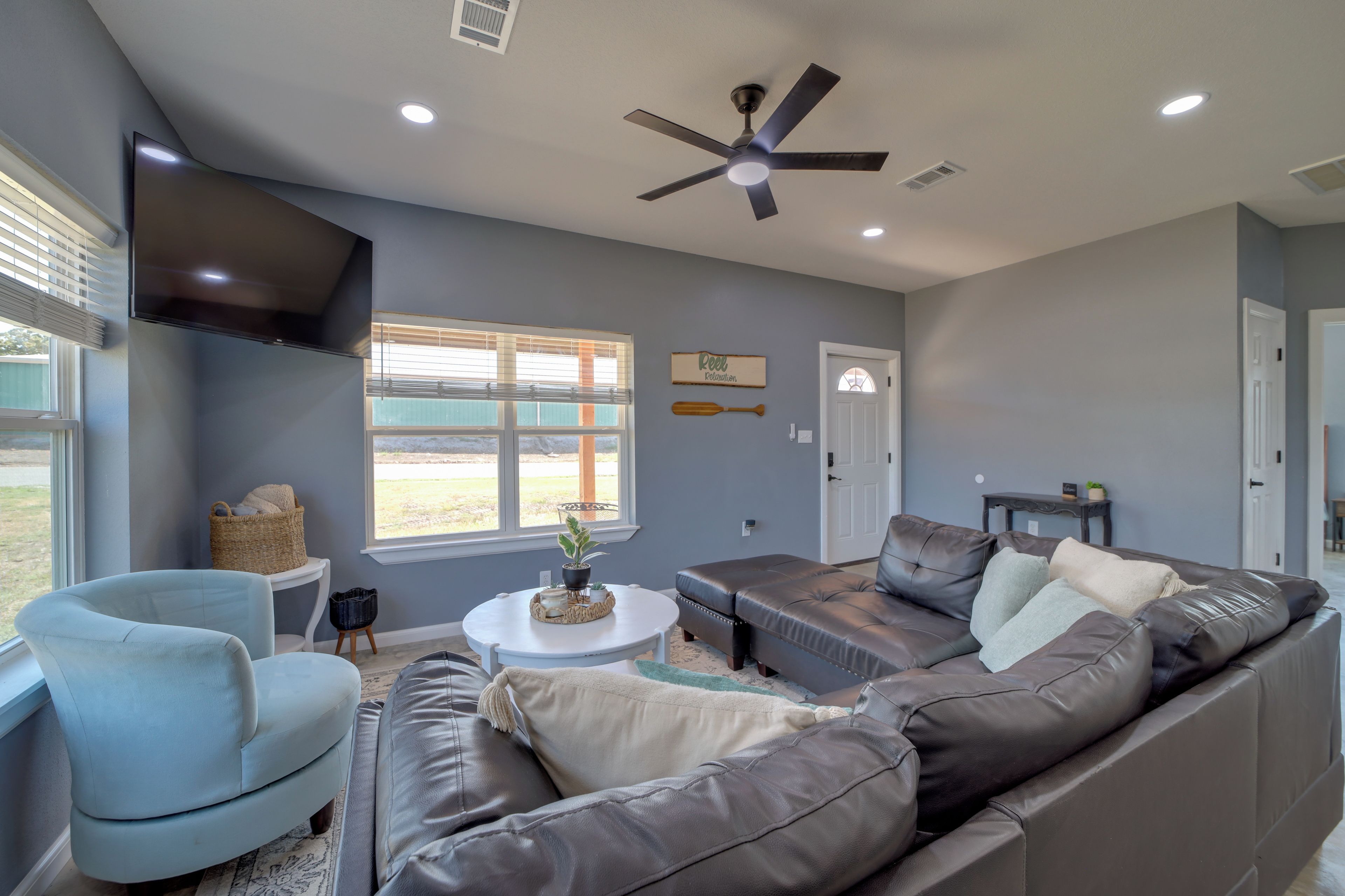 A living room with a sectional sofa, a single armchair, a coffee table, and a ceiling fan.