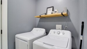 A laundry room with two front-loading washing machines and a shelf above them holding a laundry schedule, a jar of laundry detergent, and a jar of dryer sheets. - Gateway to State Park & Lake! Inviting Vian Cabin (Gore)
