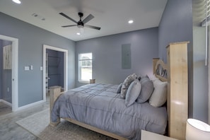 A bedroom with a bed, a ceiling fan, a window, and a door.