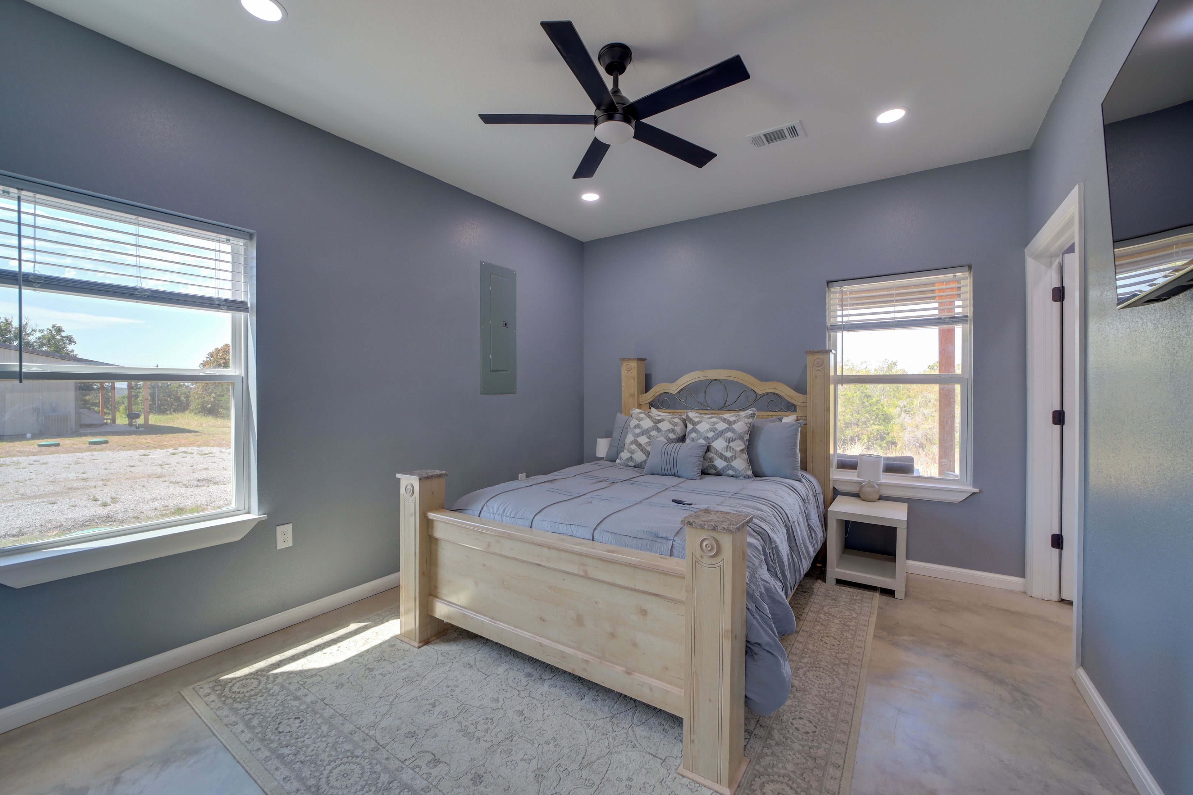 A bedroom with a bed, a nightstand, a ceiling fan, and a window.