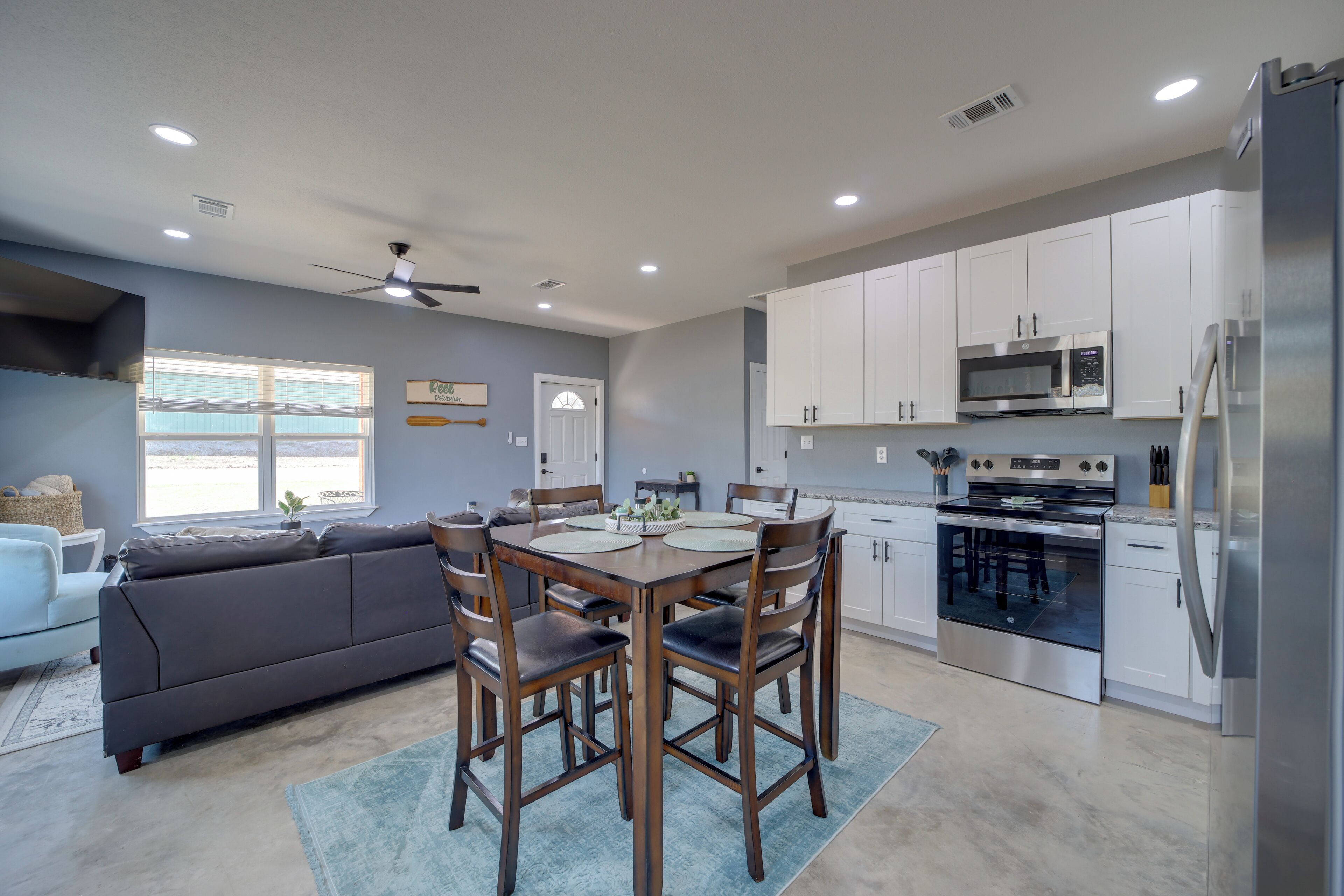 A modern kitchen with white cabinets, a stainless steel refrigerator, and a built-in microwave.