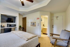Ein Hotelzimmer mit Bett, Sessel, Fernseher, Kaffeemaschine und einem kleinen Tisch mit Pflanze.