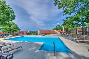 A swimming pool with lounge chairs, a lifeguard stand, and a view of buildings with red roofs. - 'above the Lake Escape' Condo in Lake Ozark (Lake Ozark)