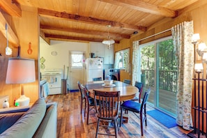 Interior acogedor de una cabaña con una mesa de comedor de madera, sillas, un sofá y una zona de cocina.