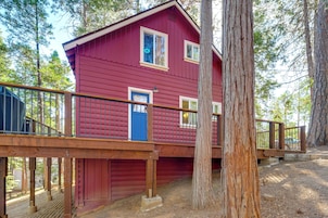A red cabin with a wooden deck and a blue door.