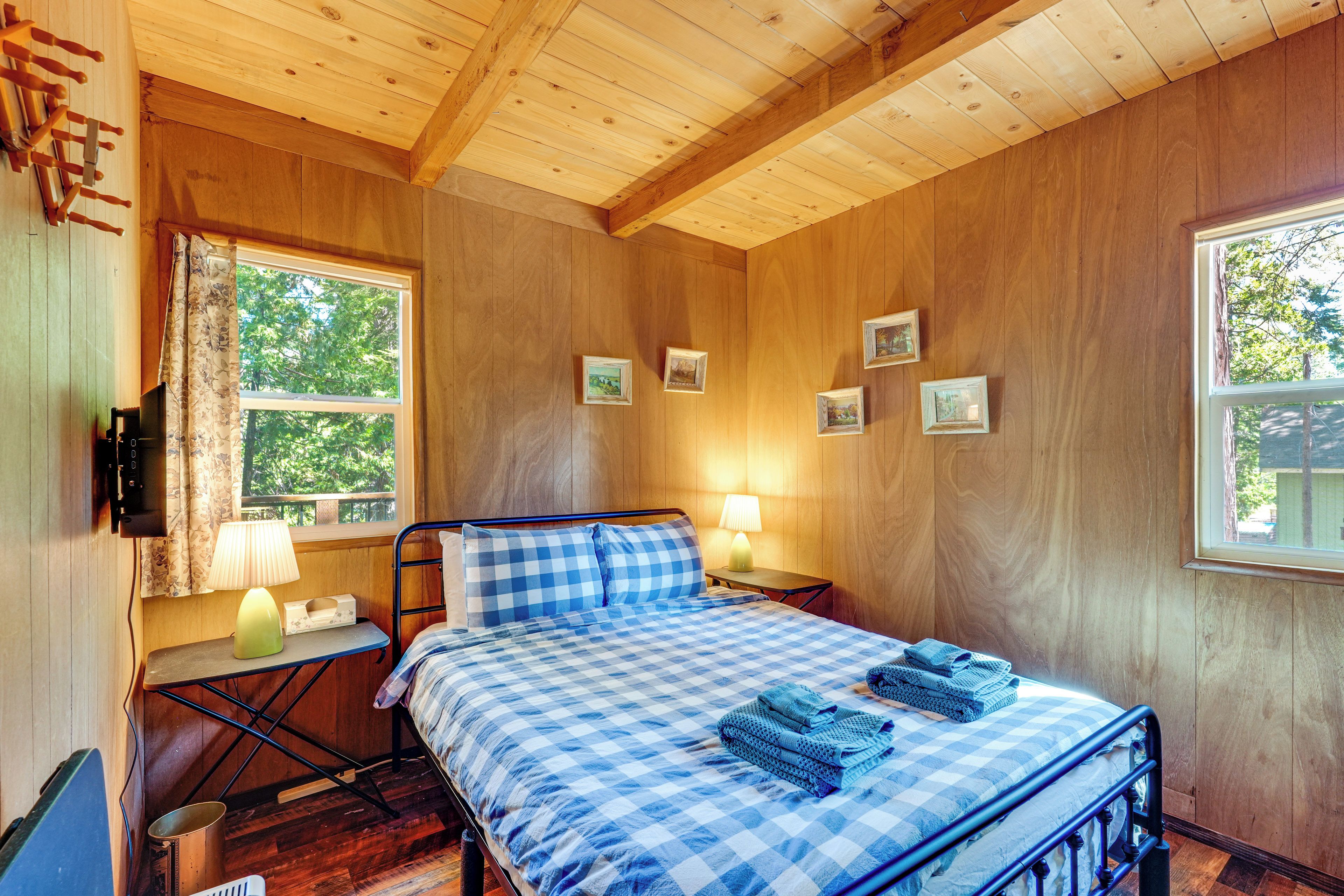 Habitación con paneles de madera, una cama, dos lámparas de noche y un ventanal con cortinas.