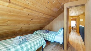 A room with two beds, wooden walls, and a sloped ceiling.