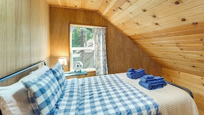 A room with a bed, a window, a fan, and a view of the outdoors.