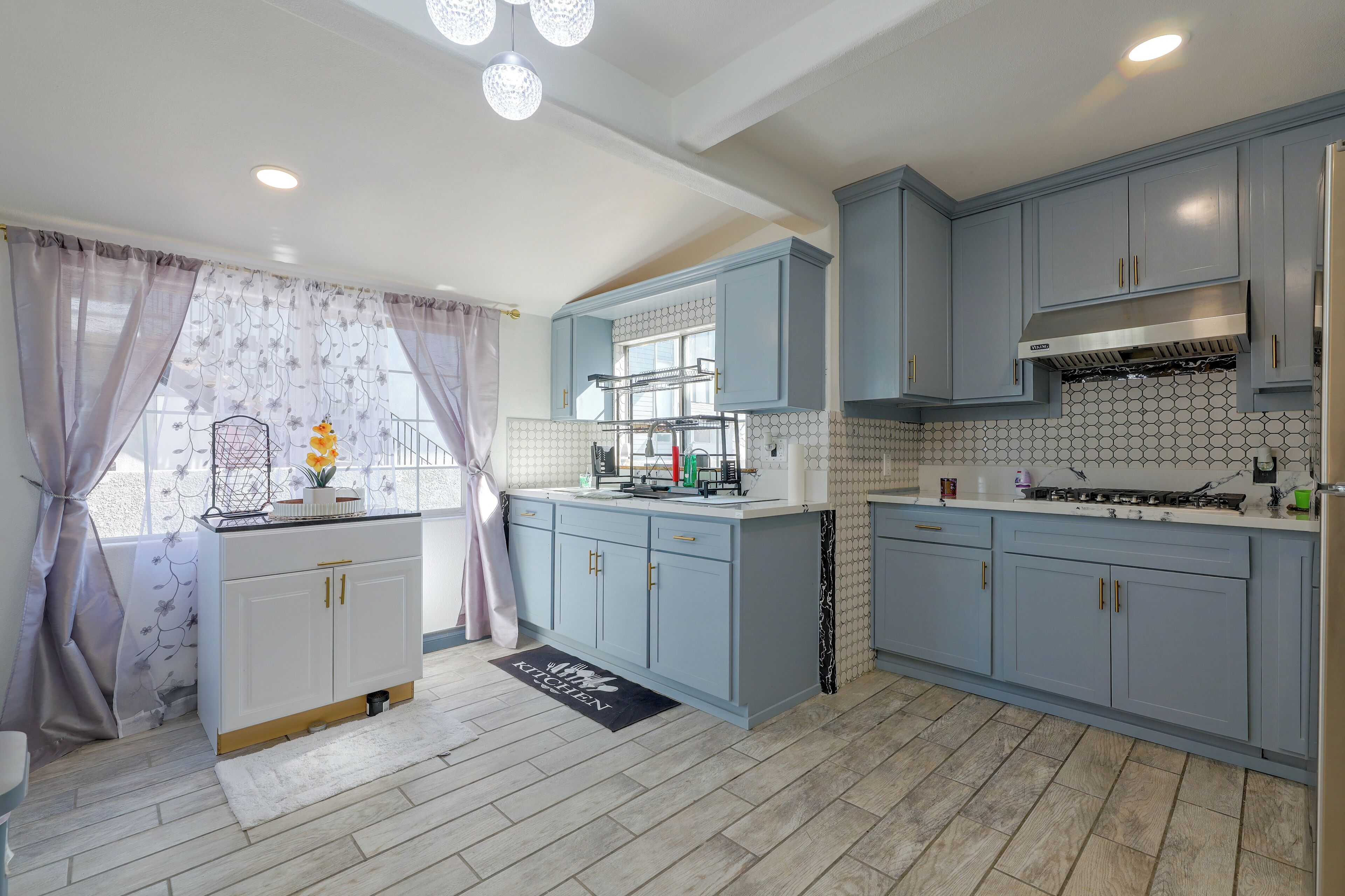 A kitchen with light blue cabinets, a white countertop, and a tiled backsplash.