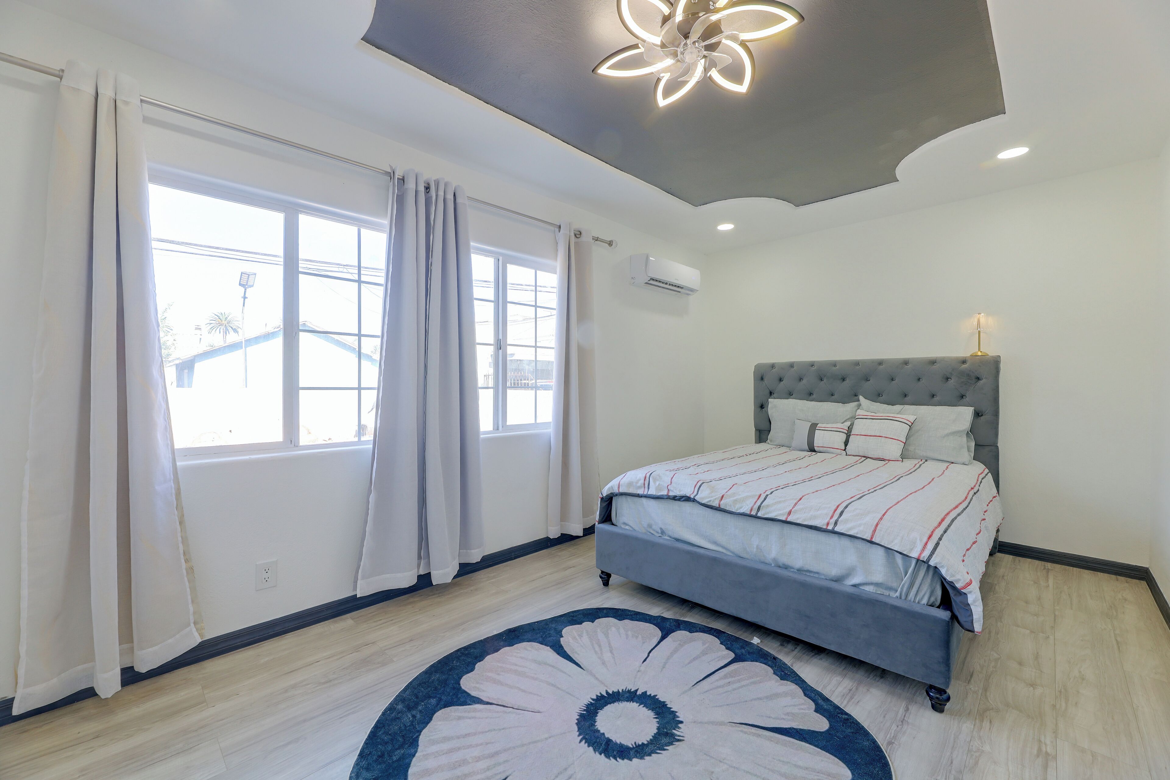 Ein Schlafzimmer mit einem Bett, einem Deckenventilator und einem Vorhangfenster.