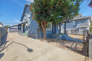 Une rue résidentielle bordée de maisons, avec un arbre et un ciel dégagé.