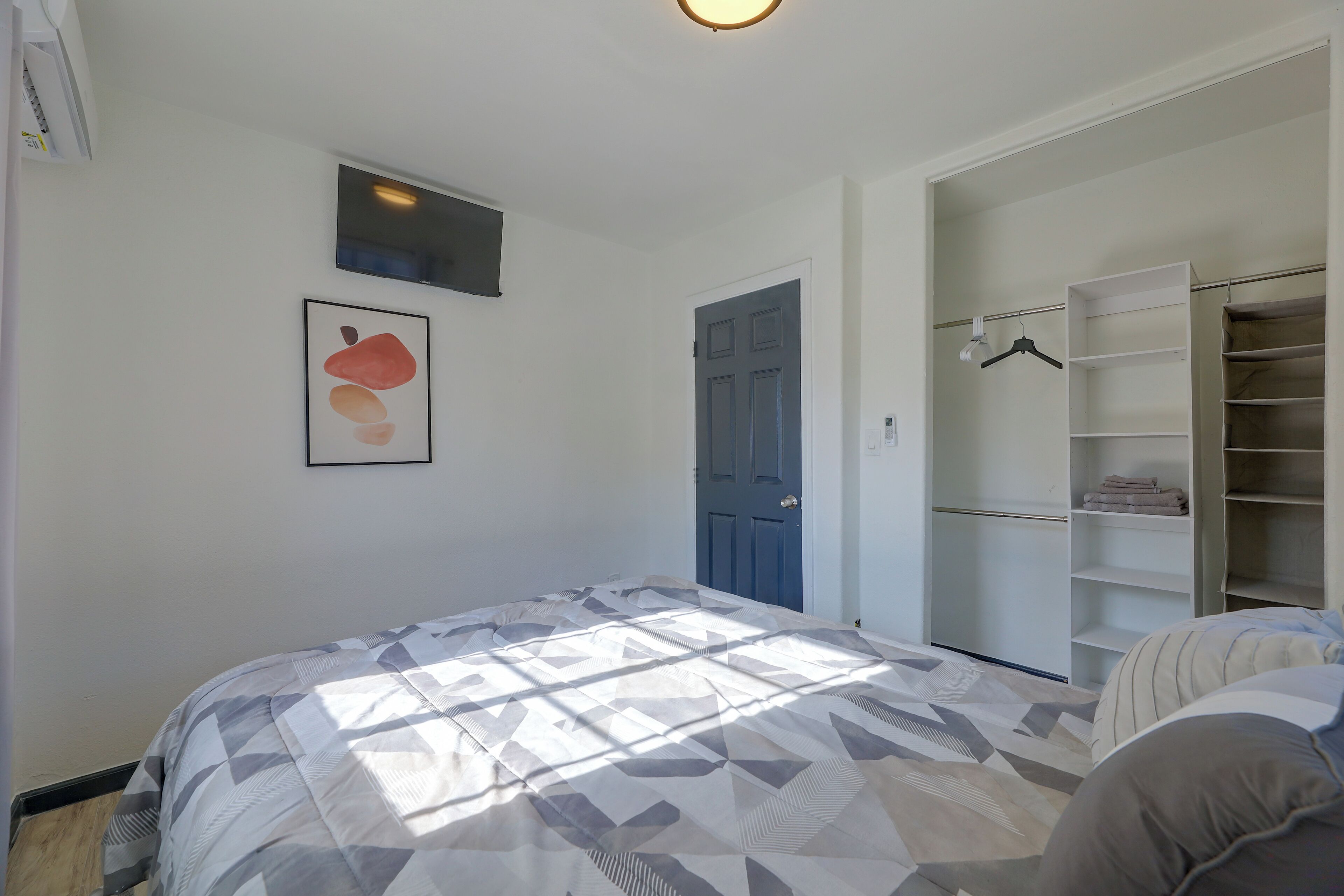 A bedroom with a bed, a wardrobe, a door, and a framed picture on the wall.