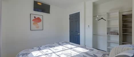 A bedroom with a bed, a wardrobe, a door, and a framed picture on the wall.