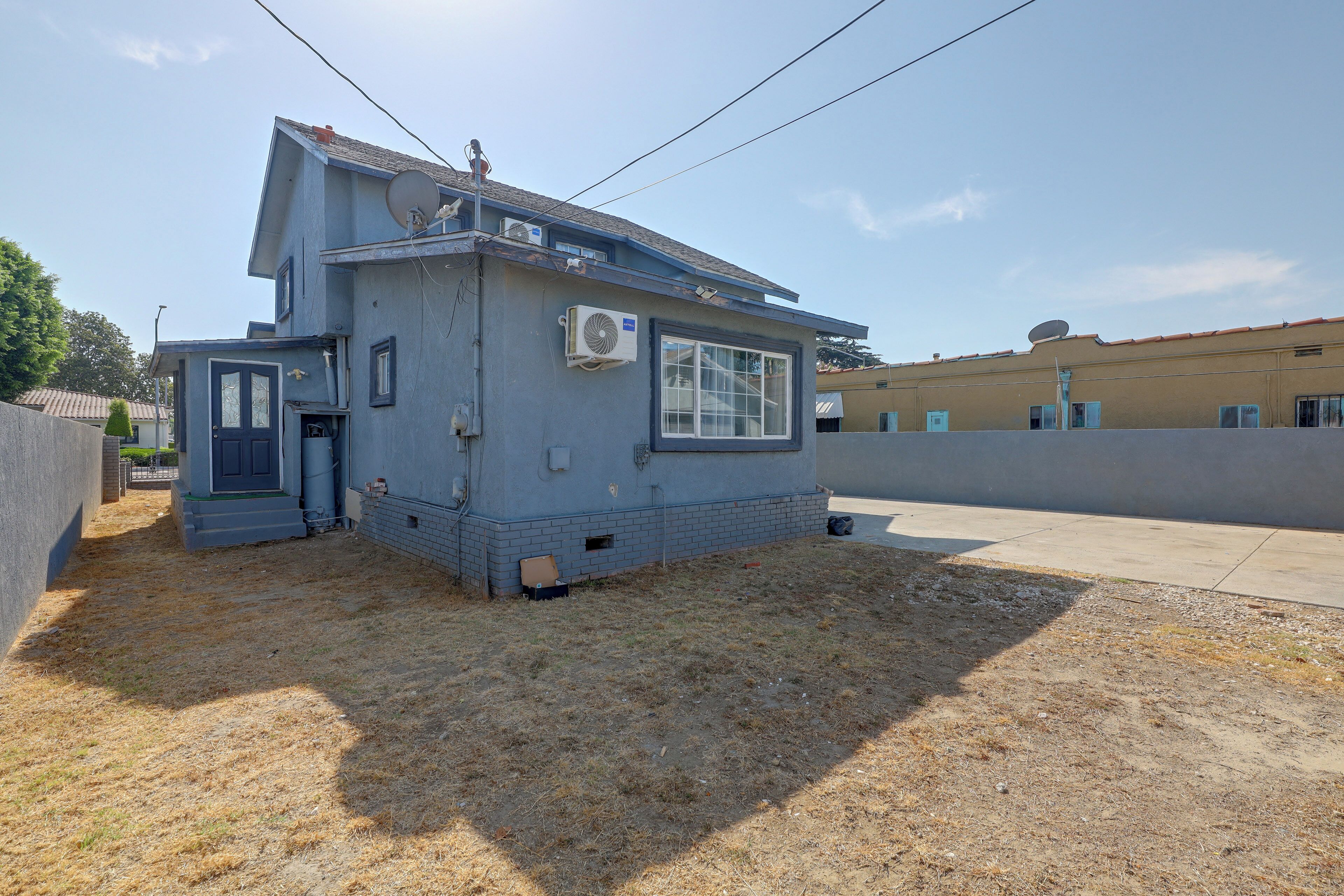 A two-story residential building with a satellite dish, a small attached garage, and a paved driveway.