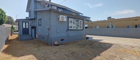 A two-story residential building with a satellite dish, a small attached garage, and a paved driveway.
