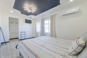 Une chambre à coucher comprenant un lit, un ventilateur de plafond, un appareil de climatisation, une télévision et une armoire.
