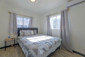 A bedroom with a bed, bedside tables, a window, and curtains. - Walkable Location! Spacious Huntington Park Home (Huntington Park)