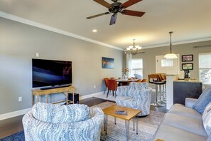 A living room with a flat-screen TV, two patterned armchairs, a sofa, a dining area with a table and chairs, and a ceiling fan. - Walk to Campus! Auburn Escape w/ Grill (Auburn)