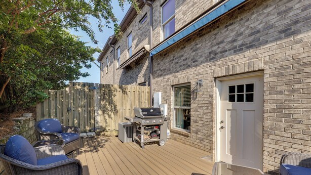 A deck with outdoor furniture, a barbecue grill, and a brick building with a white door. - Walk to Campus! Auburn Escape w/ Grill (Auburn)