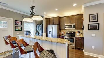 A kitchen with a central island, bar stools, a refrigerator, an oven, and a microwave.