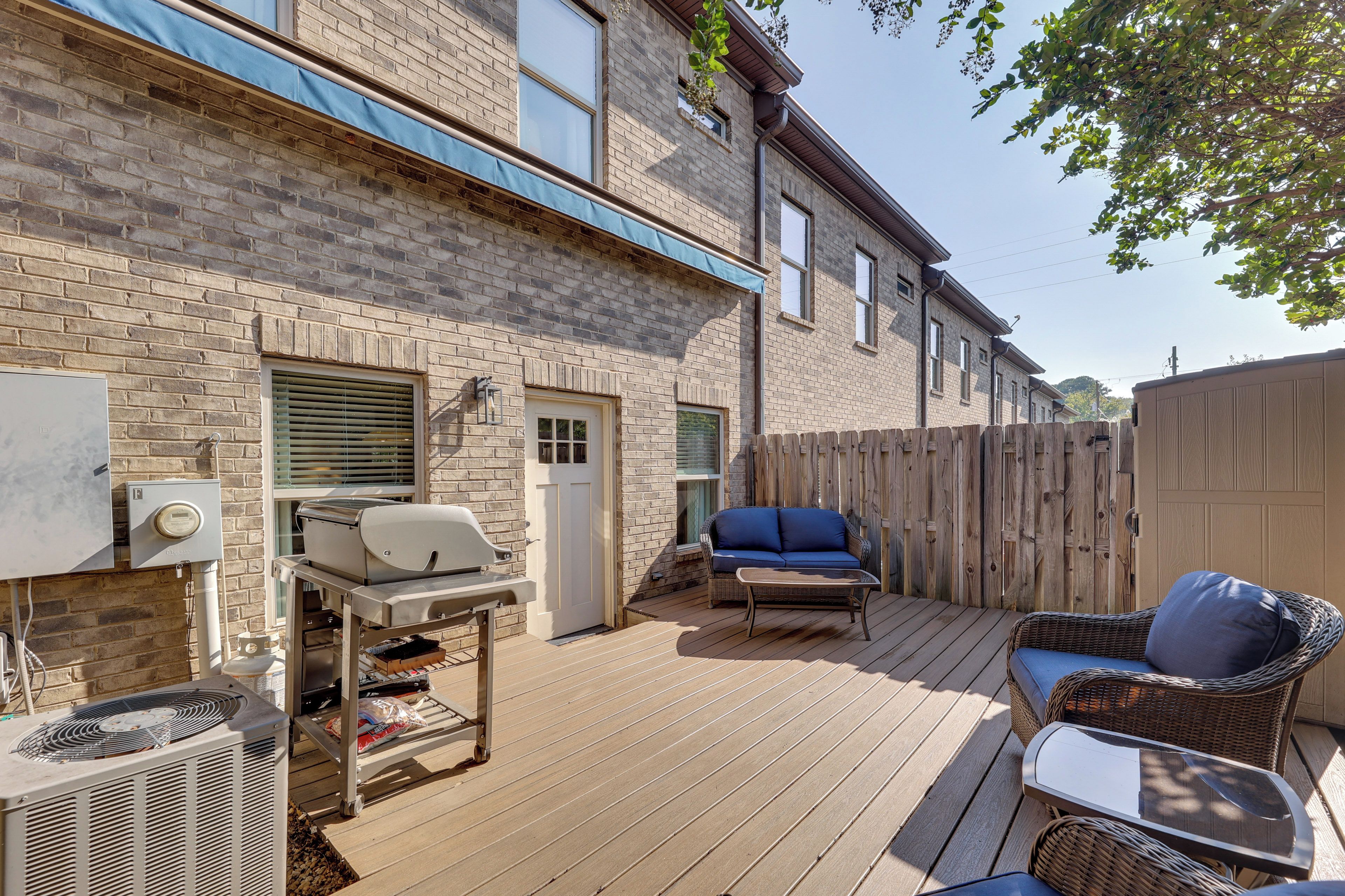 A patio with a grill, outdoor furniture, and a brick building in the background.
