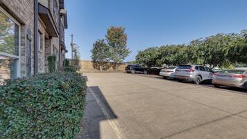 A parking lot with several cars, a building with a brick facade, and a hedge.